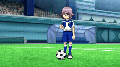 A Boy In A Soccer Uniform Stands Next To A Soccer Ball On A Field With A Tv Channel In The Background GIF