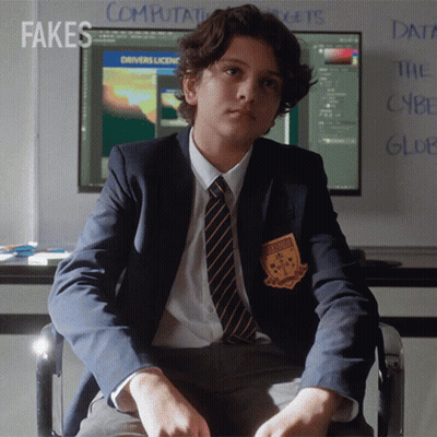 A Boy In A Suit And Tie Is Sitting In Front Of A Computer Screen With Fakes Written On The Wall Behind Him GIF