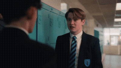 A Boy In A Suit And Tie Is Standing Next To A Boy In A Locker Room . GIF