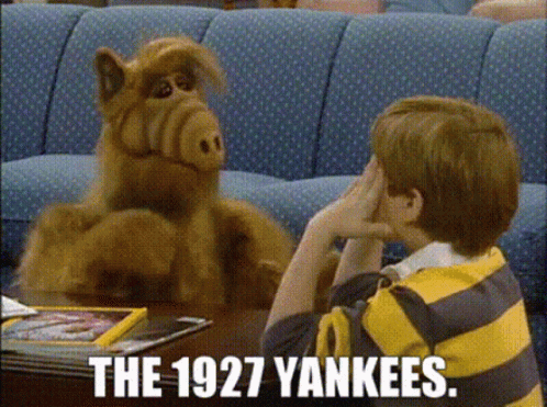A Boy In A Yellow And Black Striped Shirt Is Sitting At A Table Talking To A Stuffed Animal . GIF