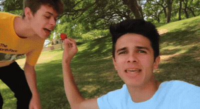 A Boy In A Yellow Shirt Is Eating A Strawberry GIF