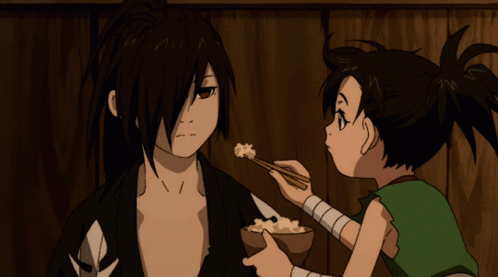 A Boy Is Feeding A Man A Bowl Of Food With Chopsticks GIF