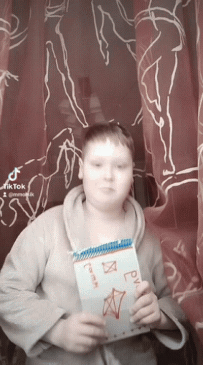A Boy Is Holding A Notebook With A Drawing On It That Says ' Rv ' On It GIF