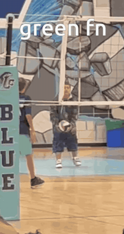 A Boy Is Holding A Volleyball In Front Of A Volleyball Net With The Words Green Fn On It . GIF