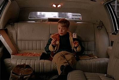 A Boy Is Sitting In The Back Seat Of A Lincoln Limousine Eating Pizza GIF
