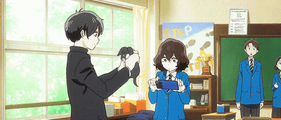 A Boy Is Taking A Picture Of A Girl In A Classroom With A Sign That Says Step In The Background . GIF