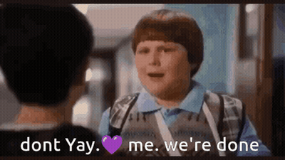 A Boy Is Talking To Another Boy In A Hallway While Holding A Purple Heart . GIF