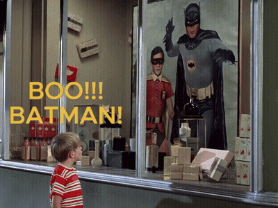 A Boy Looks Out A Window At A Batman Display GIF