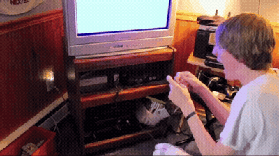 A Boy Playing A Video Game In Front Of A Tv That Says Nextel On It GIF