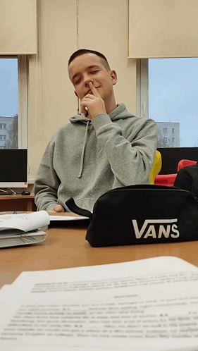 A Boy Sitting At A Desk With A Vans Pencil Case On It GIF