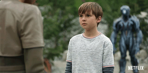 A Boy Stands In Front Of A Statue That Says Netflix On The Bottom GIF