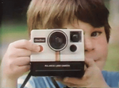 A Boy Taking A Picture With A Polaroid Land Camera GIF