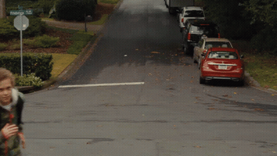 A Boy Walking Down A Street With A Sign That Says Federal St. GIF