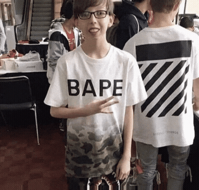 A Boy Wearing A Bape T-Shirt Stands In A Crowd Of People GIF