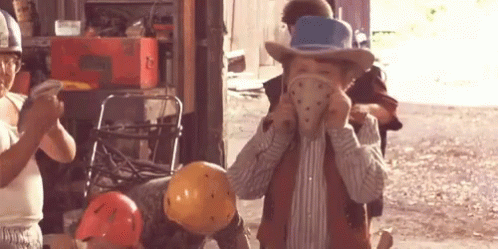 A Boy Wearing A Cowboy Hat Is Holding A Helmet In His Hand GIF