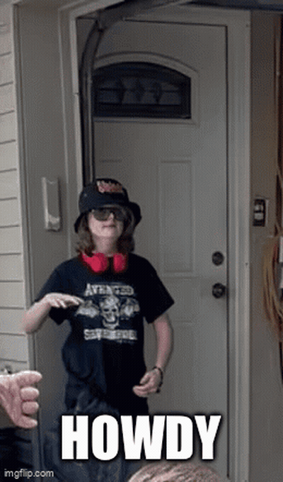 A Boy Wearing A Hat And Headphones Is Standing In Front Of A Door With The Word Howdy Written On It GIF