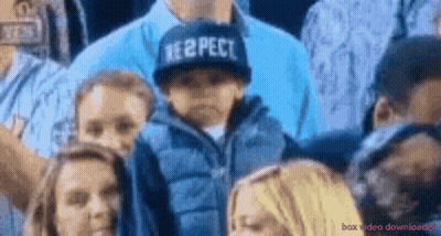 A Boy Wearing A Hat That Says Respect Stands In A Crowd GIF