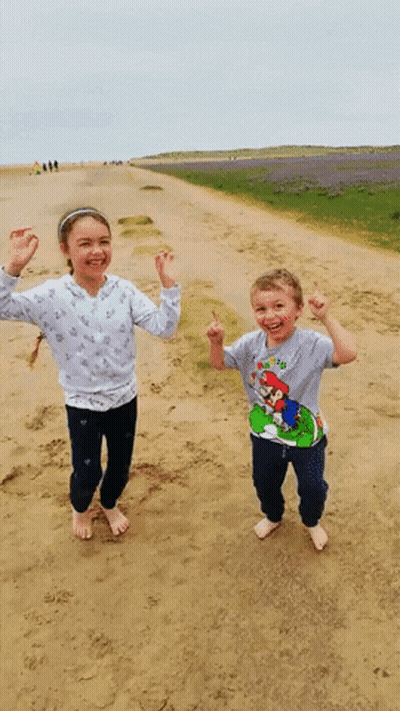 A Boy Wearing A Mario Shirt Is Standing Next To A Girl On A Dirt Road GIF