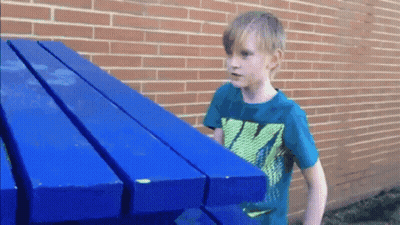 A Boy Wearing A Nike Shirt Holds A Blue Table GIF