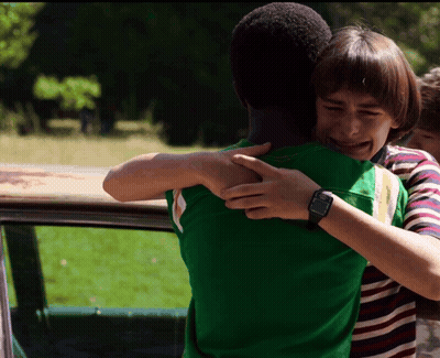 A Boy Wearing A Watch Is Hugging Another Boy In A Green Shirt GIF