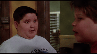 A Boy Wearing A White Shirt That Says Carolina Talks To Another Boy GIF