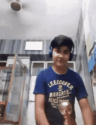 A Boy Wearing Headphones And A Lee Cooper Shirt Is Holding A Trophy GIF