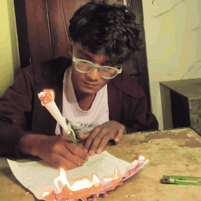 A Boy With Glasses Is Writing On A Piece Of Paper GIF