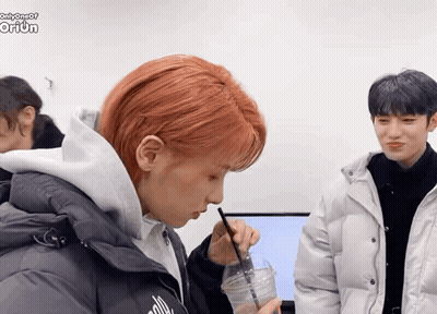 A Boy With Red Hair Is Drinking From A Cup With A Straw While Another Boy Looks On GIF