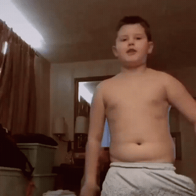 A Boy Without A Shirt Is Standing In A Room GIF