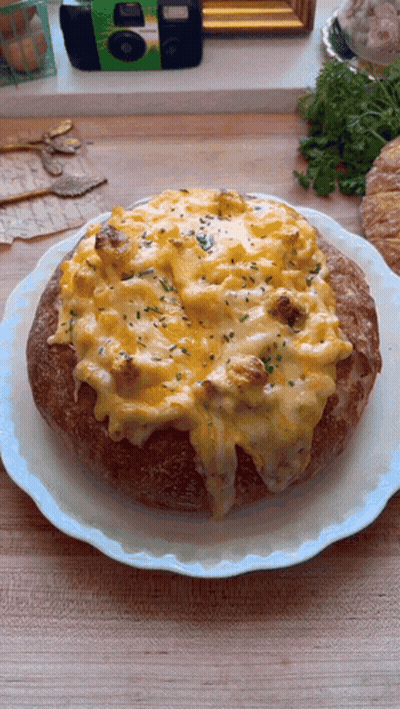 A Bread Bowl Filled With Macaroni And Cheese Is On A Plate GIF