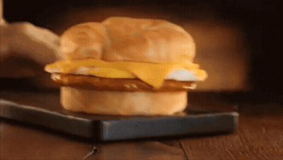 A Breakfast Sandwich On A Croissant On A Cutting Board GIF