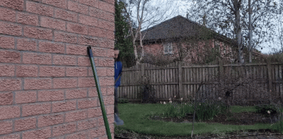 A Brick Wall With A Hose Attached To It In Front Of A House GIF