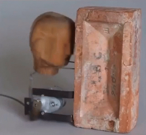 A Brick With The Number 3 On It Is Next To A Wooden Head GIF