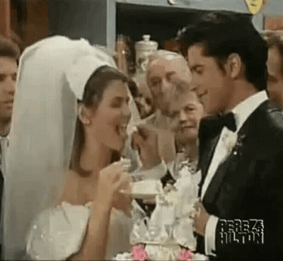 A Bride And Groom Are Cutting Their Wedding Cake While A Group Of People Watch . GIF