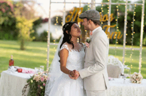 A Bride And Groom Are Dancing In Front Of A Sign That Says Maria And Timo GIF