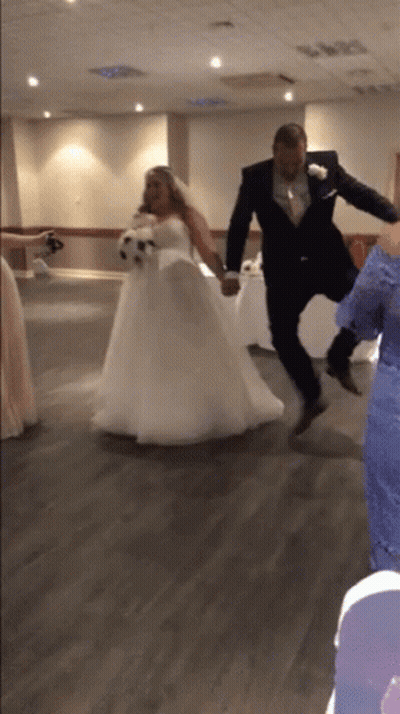A Bride And Groom Are Jumping In The Air Holding Hands GIF