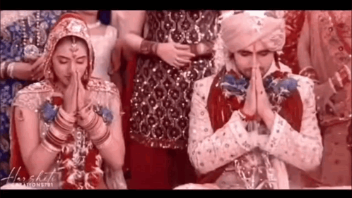 A Bride And Groom Are Praying With Their Hands Folded In Front Of Their Faces . GIF