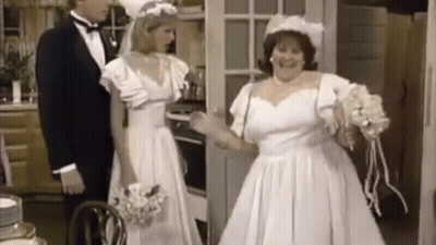 A Bride And Groom Are Standing In A Kitchen . GIF