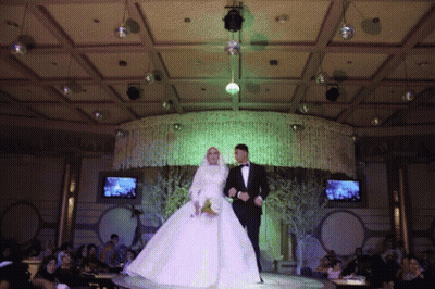 A Bride And Groom Are Walking Down The Aisle At A Wedding Reception GIF