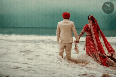 A Bride And Groom Holding Hands In The Ocean With A Watermark That Says ' Tropicana ' On It GIF