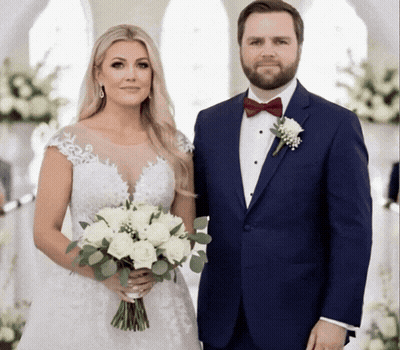 A Bride And Groom Pose For A Picture While The Bride Is Holding A Bouquet Of White Flowers GIF