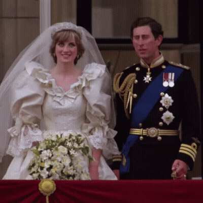 A Bride And Groom Standing Next To Each Other On Their Balcony GIF
