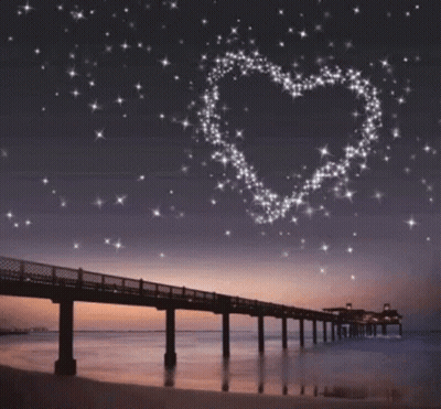 A Bridge Over A Body Of Water With A Heart Made Of Stars In The Sky GIF