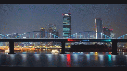 A Bridge Over A Body Of Water With Buildings In The Background GIF