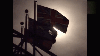A British Flag Is Silhouetted Against A Gray Sky GIF