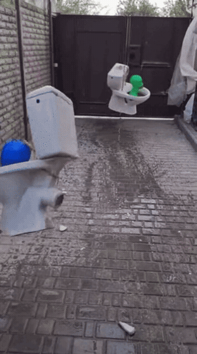 A Broken Toilet Sits On A Brick Sidewalk GIF