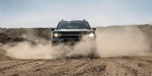 A Bronco Is Driving Through A Dirt Field GIF