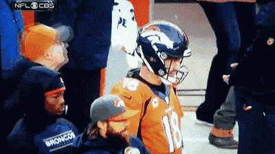 A Broncos Football Player Wearing A Helmet Stands In Front Of A Crowd GIF