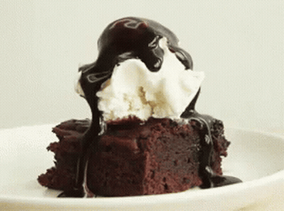 A Brownie With Ice Cream And Chocolate Sauce On Top Of It GIF