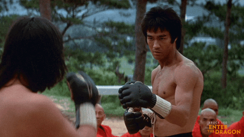 A Bruce Lee Enter The Dragon Poster Shows Two Men Boxing GIF